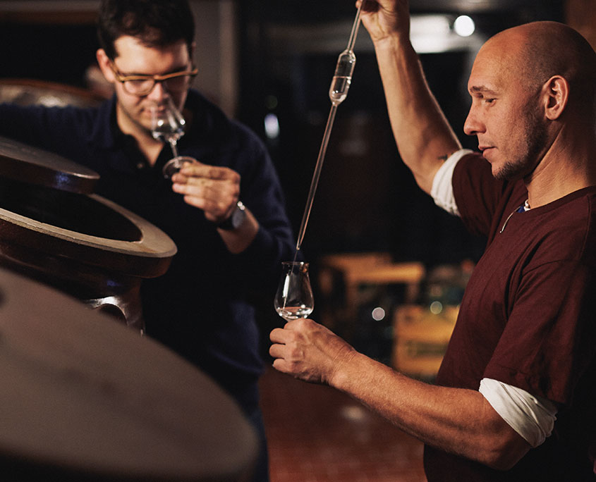 prinz-hafelebrand-produktion-kontrolle-845x684 Zwei Personen degustieren einen Edelbrand aus dem Steingutbehälter.